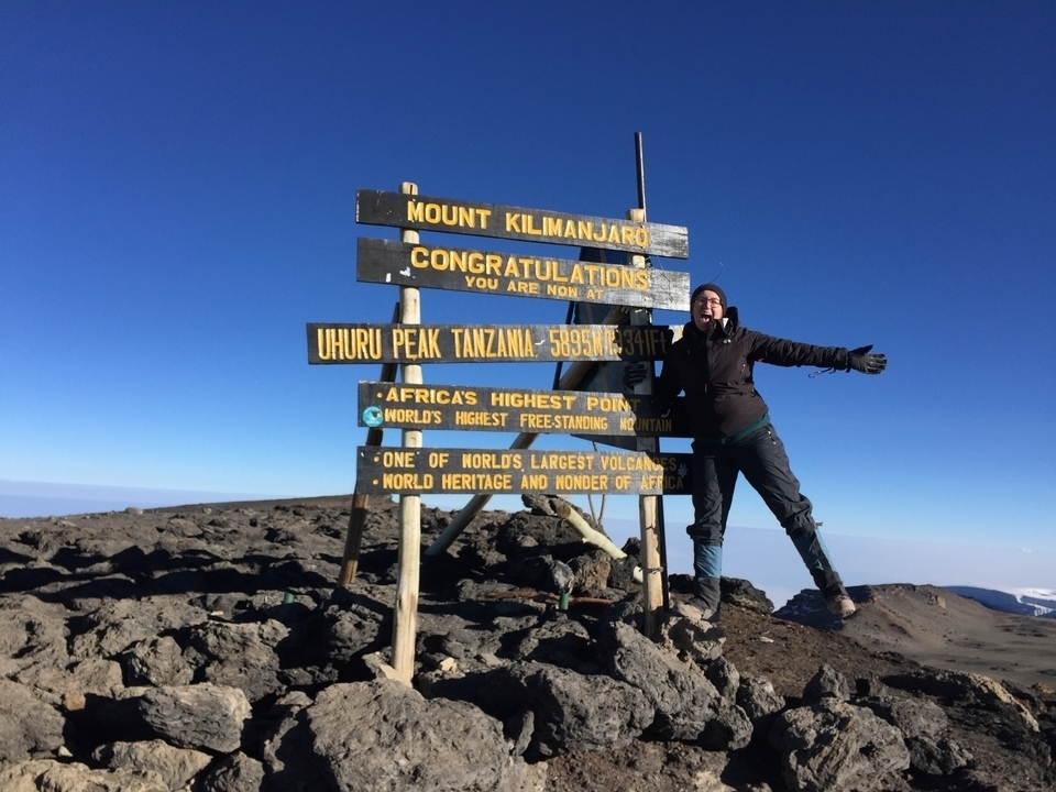 Lara standing on top of Mount Kilimanjaro next to the summit sign